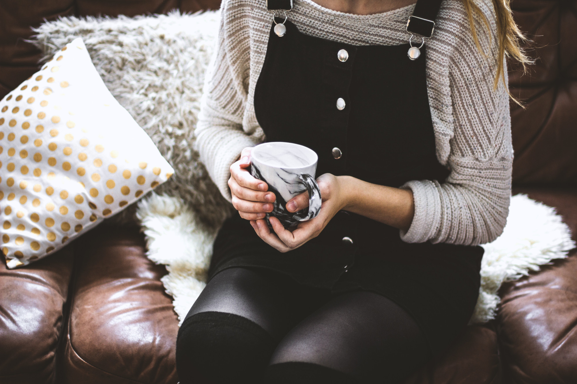 Photo of someone holding a cup of tea on a sofa